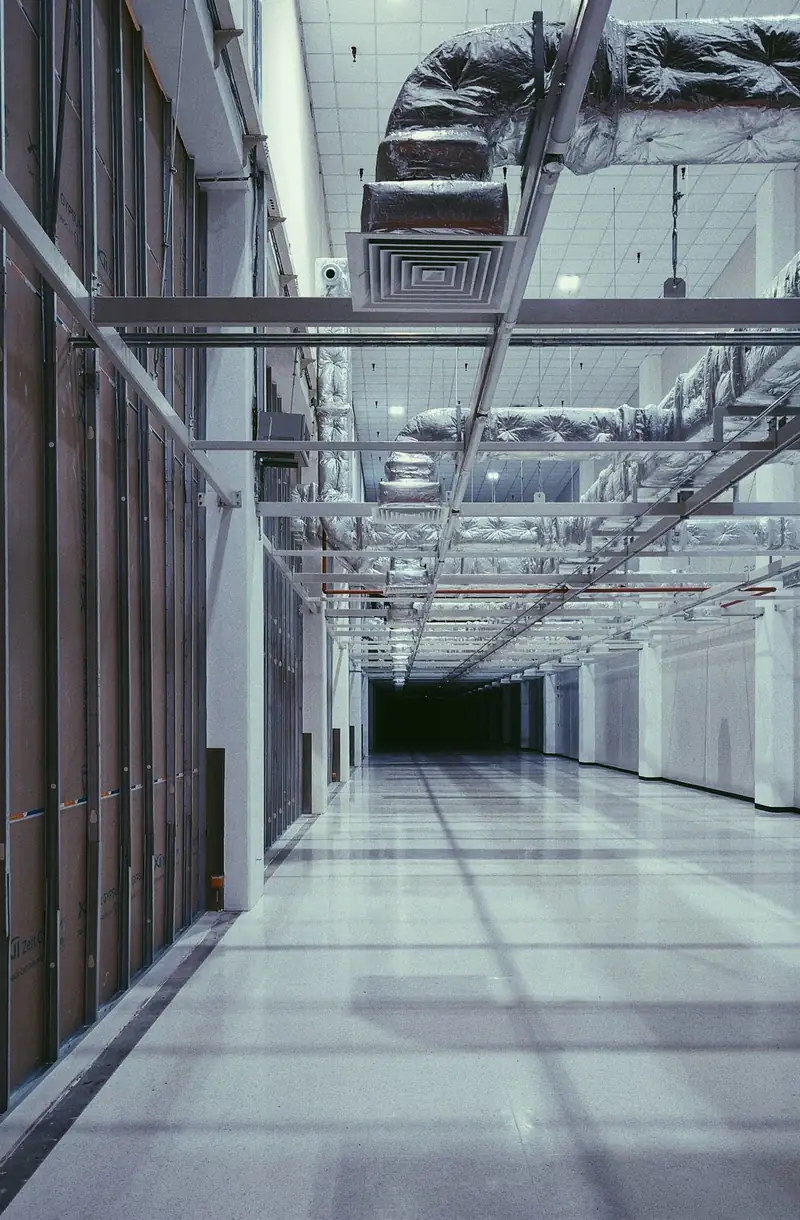 Koridor gedung dengan ducting dan pipa ekspos