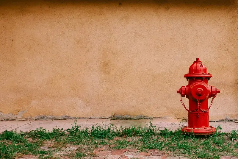 Hydrant pillar merah di samping dinding gedung