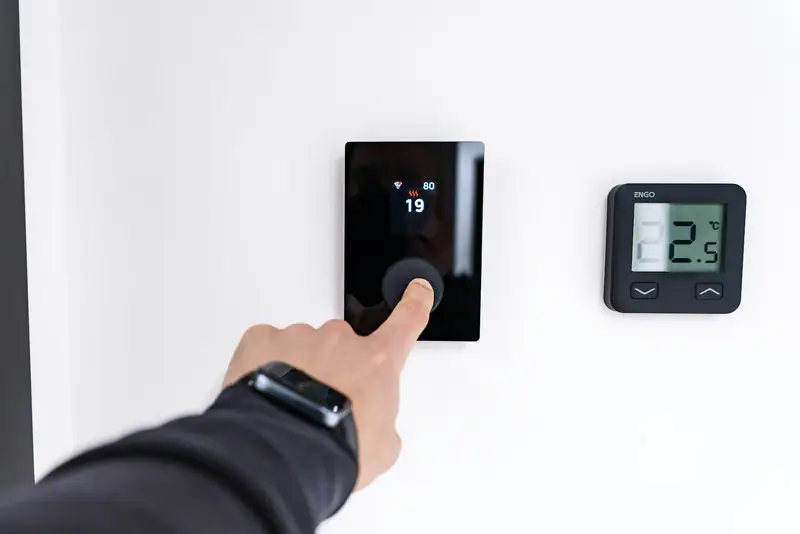 Technician adjusting a digital wall thermostat